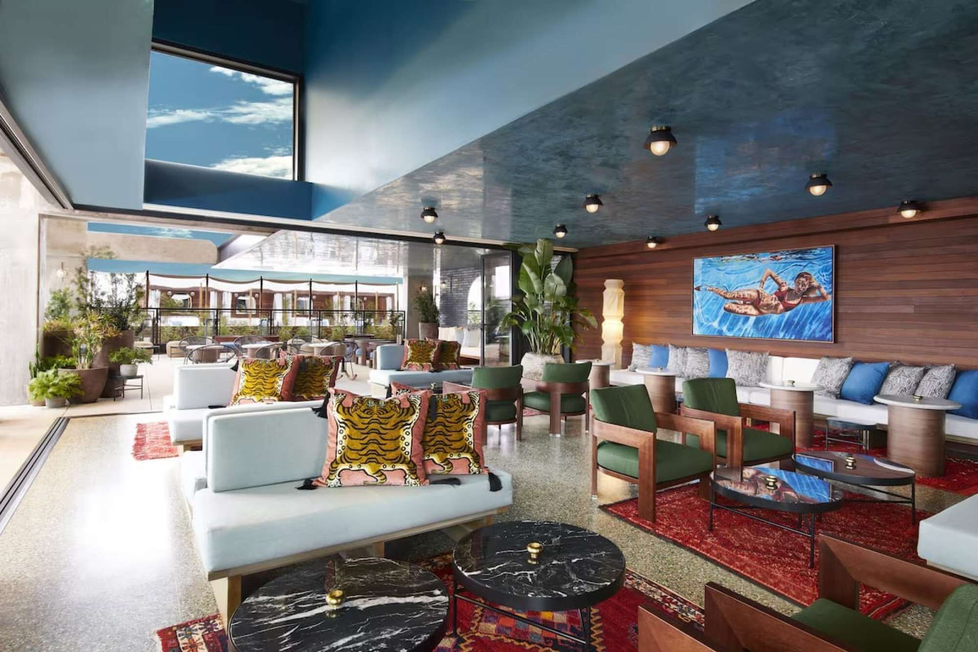 A spacious lobby with a modern design, featuring a seating area with sofas and chairs, a coffee table, and a large window offering a view of the outdoors.
