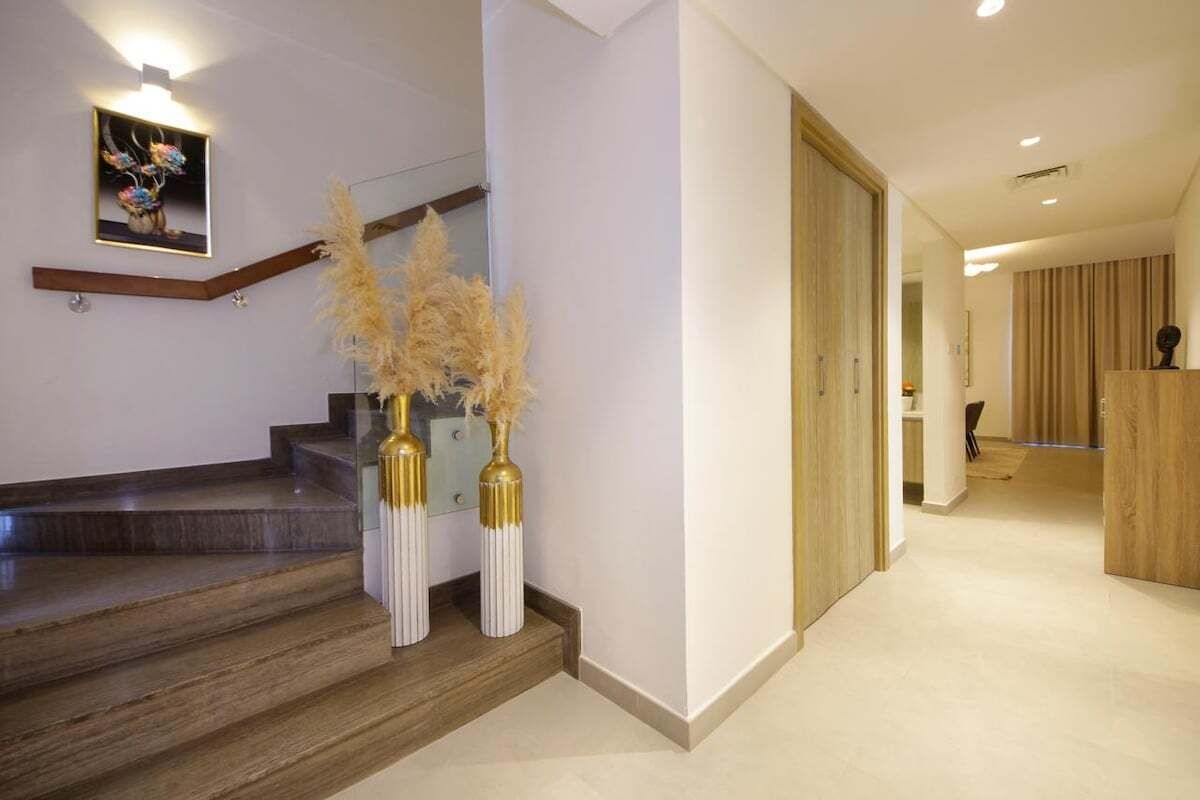 Un intérieur moderne avec un escalier, une porte en bois et un tableau encadré au mur.