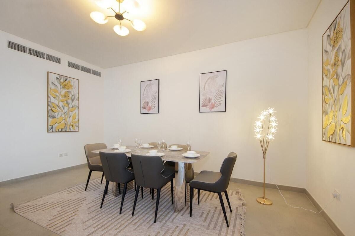 A dining area with a round table, six chairs, and a floor lamp.