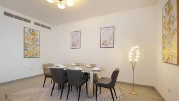 A dining area with a round table, six chairs, and a floor lamp.