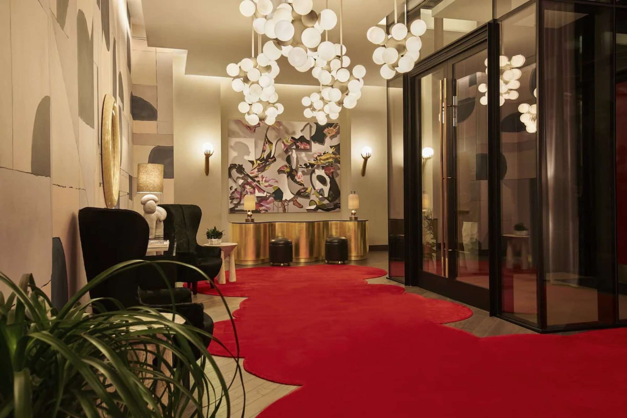 A lobby with a red carpet, a reception desk, a black armchair, and a large abstract painting.