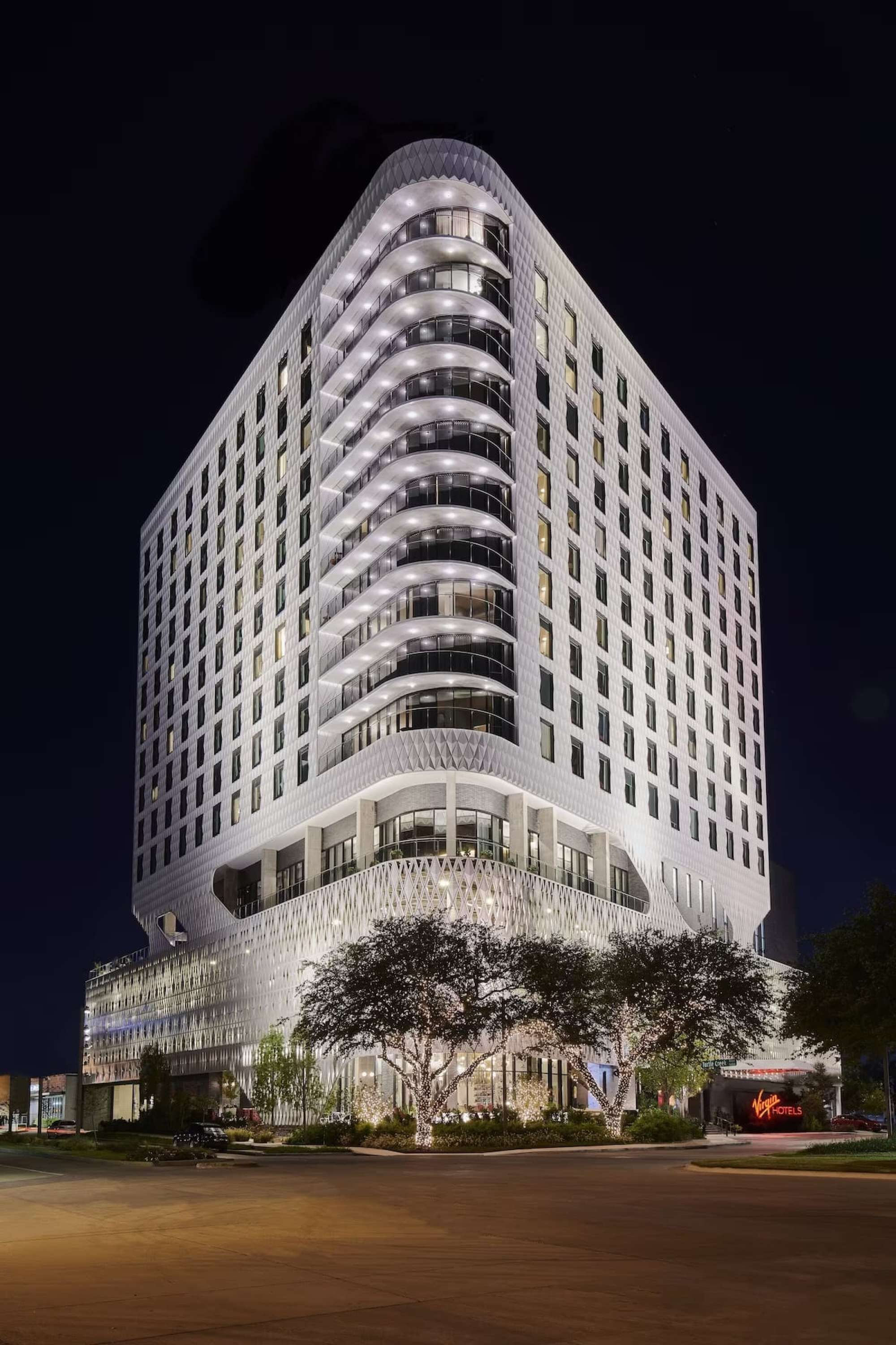 A modern hotel with a curved facade, multiple balconies, and a prominent Virgin Hotels sign.