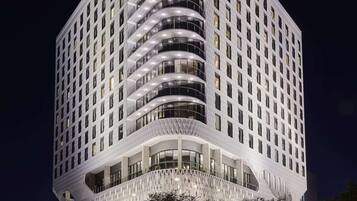 A modern hotel with a curved facade, multiple balconies, and a prominent Virgin Hotels sign.