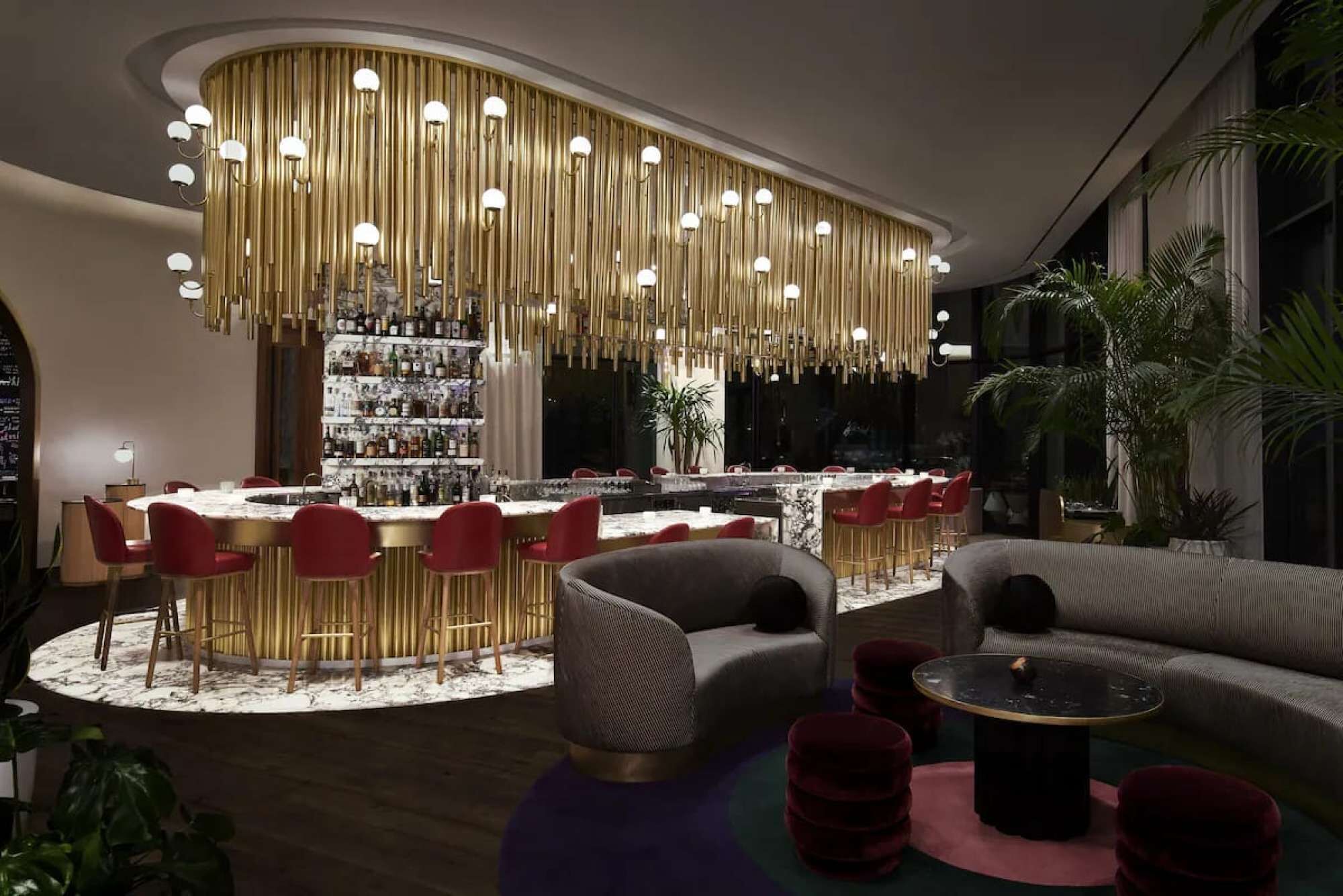 A modern bar area with a circular seating arrangement, a central bar counter, and a hanging light fixture.