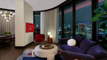 A modern living room with a city view, a red chair, a purple sofa, and a round coffee table.