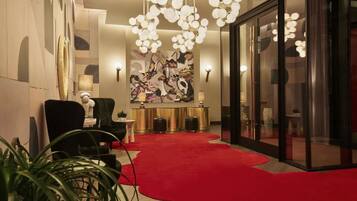 A lobby with a red carpet, a reception desk, a black armchair, and a large abstract painting.