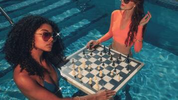 Two individuals playing chess in a swimming pool.