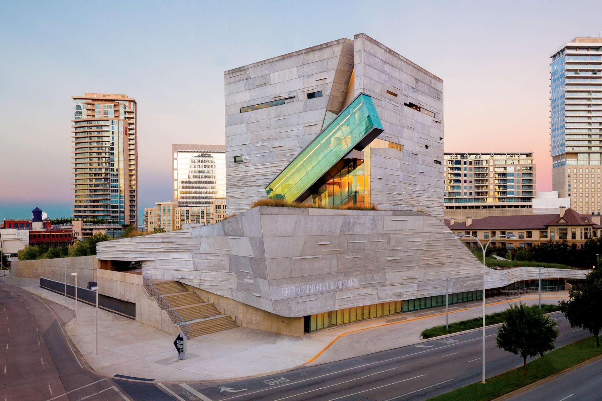 A modern building with a unique angular design, featuring a prominent glass facade and a sloped roof.