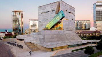 A modern building with a unique angular design, featuring a prominent glass facade and a sloped roof.