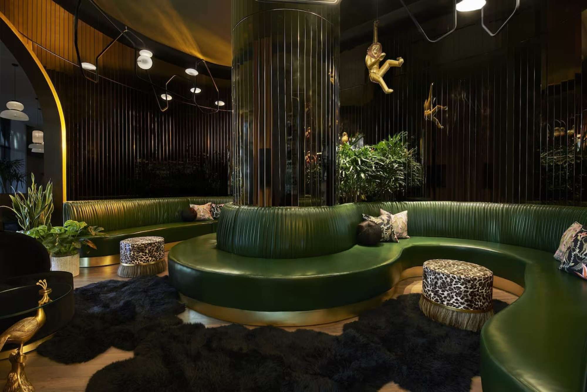 A modern lounge area with green curved seating, a central column, and decorative lighting.