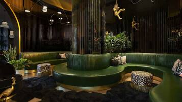 A modern lounge area with green curved seating, a central column, and decorative lighting.