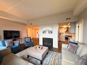 Ein modernes Wohnzimmer mit Fernseher, Sofas und einem Kamin.