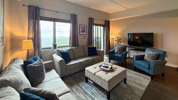 A modern living room with a sofa, armchairs, a coffee table, and a TV. - 6th floor condo- hot tub- views of Grandfather Mountain (Sugar Mountain)