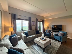 Ein modernes Wohnzimmer mit einer Couch, Sesseln, einem Couchtisch und einem Fernseher.