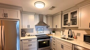 A modern kitchen with stainless steel appliances, white cabinetry, and a central island. - 6th floor condo- hot tub- views of Grandfather Mountain (Sugar Mountain)