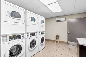 A laundry room with stacked washers and dryers, a stool, and a door. - Near Antelope Canyon + Free Breakfast. Pool. Gym. (Page)
