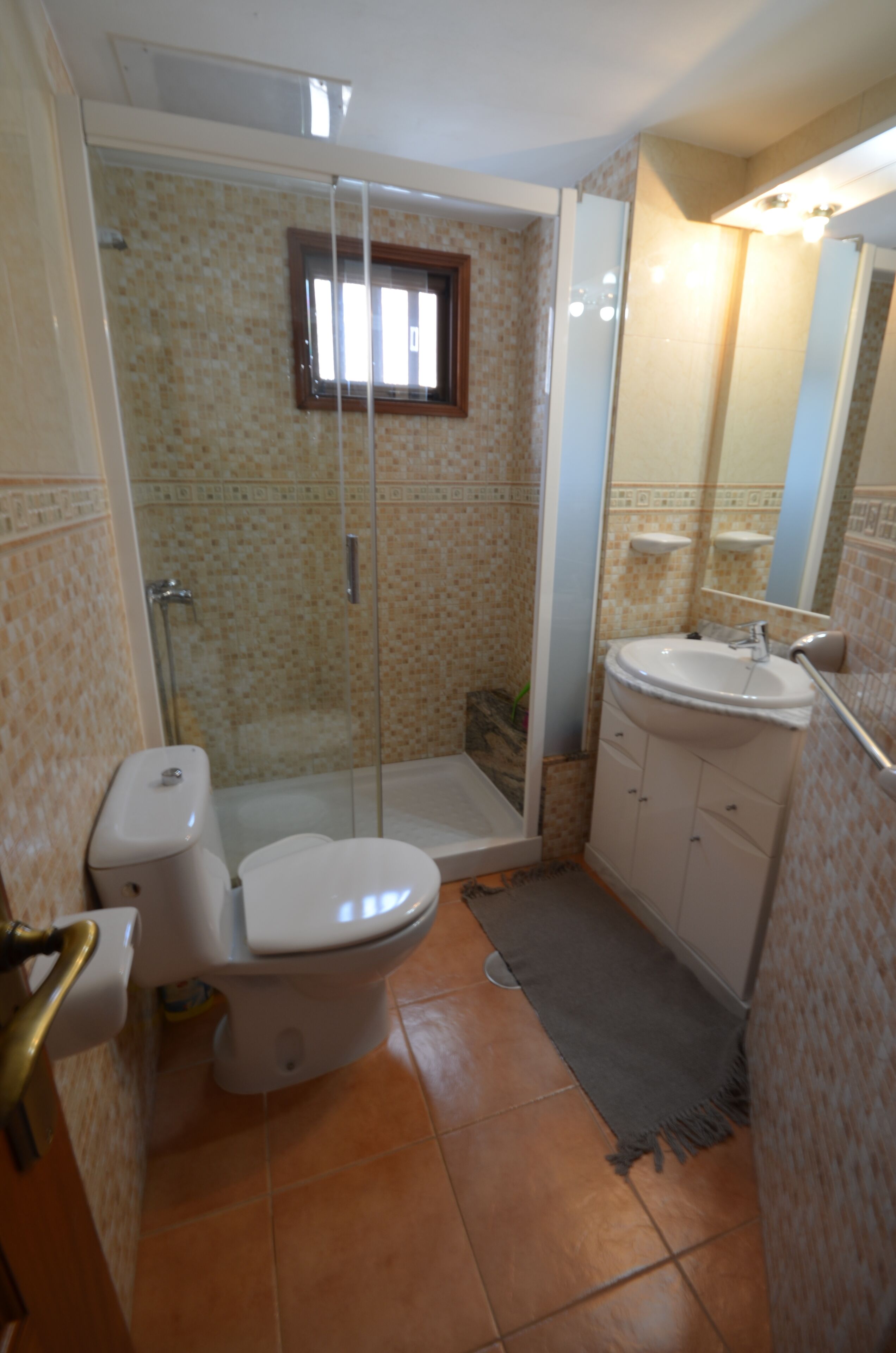 A bathroom with a toilet, shower, and sink.