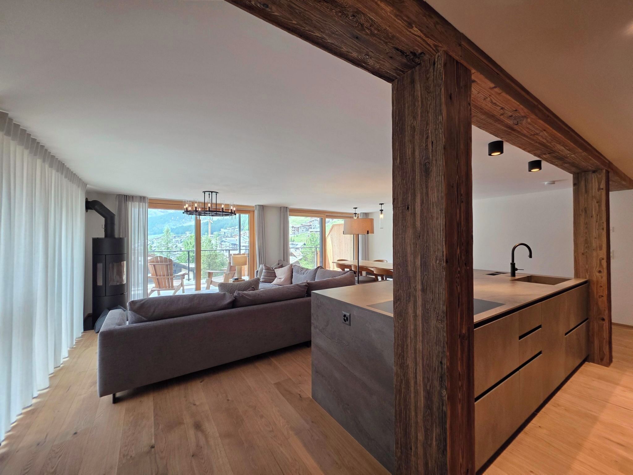 A modern living room with a large sofa, a dining area, and a kitchen island.