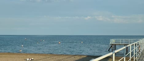 A beach with a wooden walkway and a metal railing.