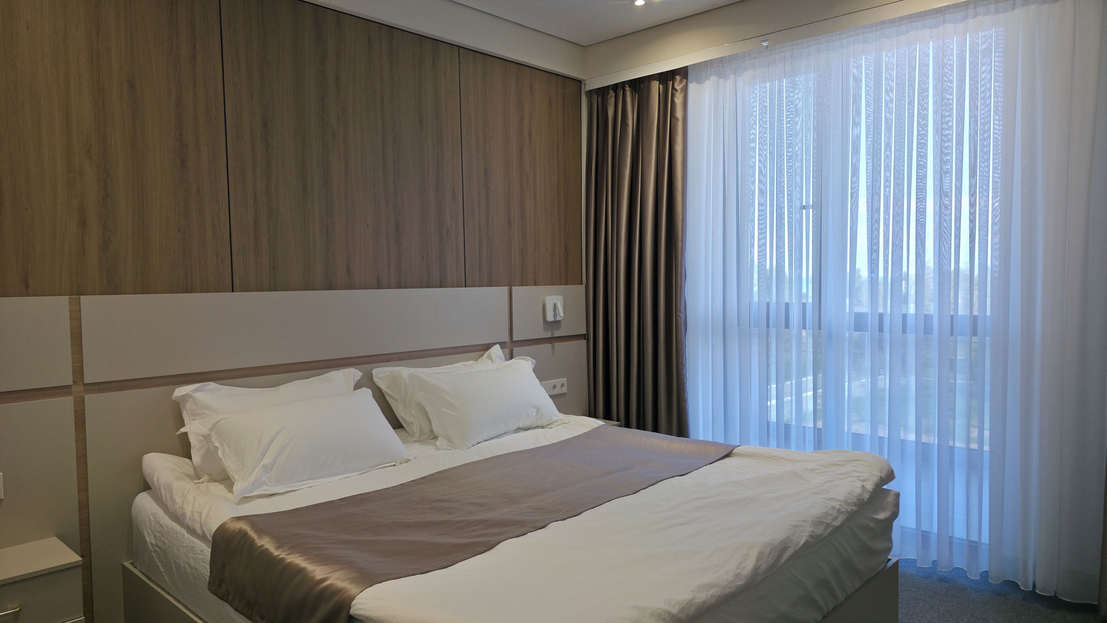 Ein Hotelzimmer mit einem Bett, einem Nachttisch und einem Fenster mit Vorhängen.