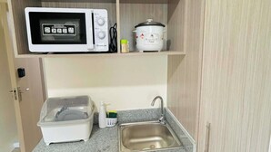 A compact kitchenette with a microwave, slow cooker, and a small sink. - City Comfort at Urban Deca Towers Cubao (Quezon City)
