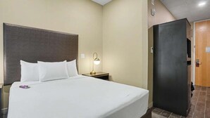 A hotel room with a bed, bedside lamp, and a door leading to another room.