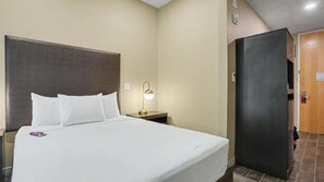A hotel room with a bed, bedside lamp, and a door leading to another room.