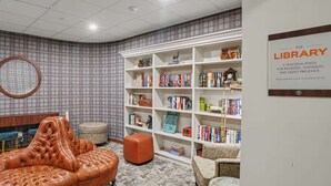 A library with bookshelves, a leather armchair, and a circular mirror.