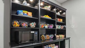 Une cuisine équipée d’un four à micro-ondes encastré et de plusieurs étagères remplies de collations et de condiments.