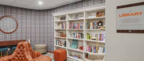 Une bibliothèque avec des étagères, un fauteuil en cuir et un miroir rond.
