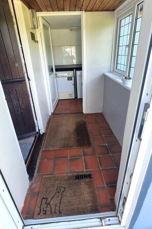 Un estrecho vestíbulo con piso de baldosas que conduce a una pequeña cocina.