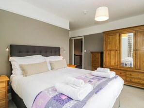 Ein Schlafzimmer mit einem großen Bett, einem Holzschrank, einem Spiegel und einer Pendelleuchte.
