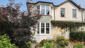 Une maison à deux étages avec un jardin à l’avant.