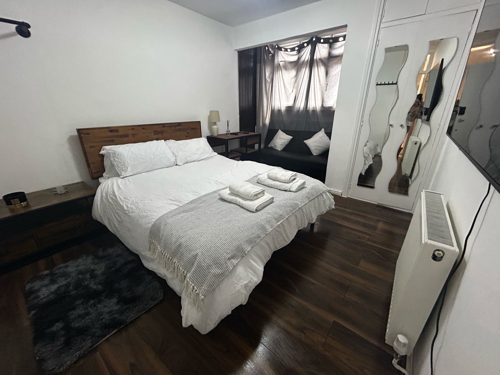 Une chambre d’hôtel avec un lit, une table de chevet, une lampe et un miroir.