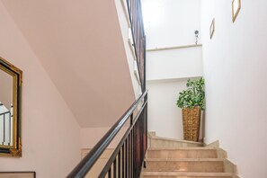A staircase with a handrail, a potted plant, and a wall-mounted light fixture. - Casa del Sole - Menfi (Menfi)