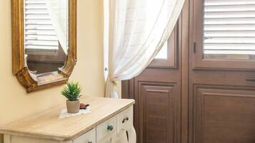 A room with a wooden dresser, a mirror, a potted plant, and a door with a window.