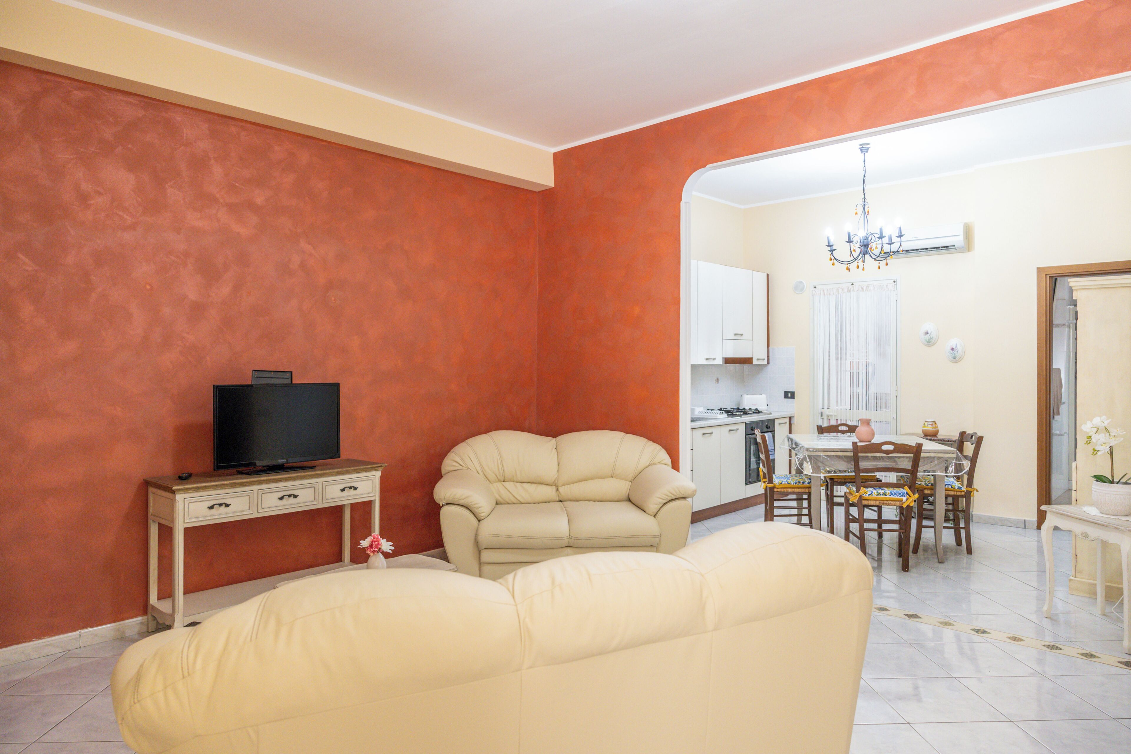 A living room with a sofa, a television on a stand, and a dining area with a table and chairs.