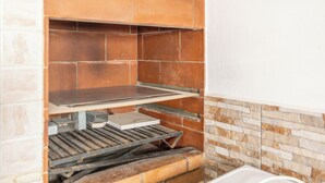 Eine Küche mit Ziegelrückwand, einem Metallregal und einer weißen Arbeitsplatte.