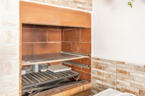 Eine Küche mit Ziegelrückwand, einem Metallregal und einer weißen Arbeitsplatte.