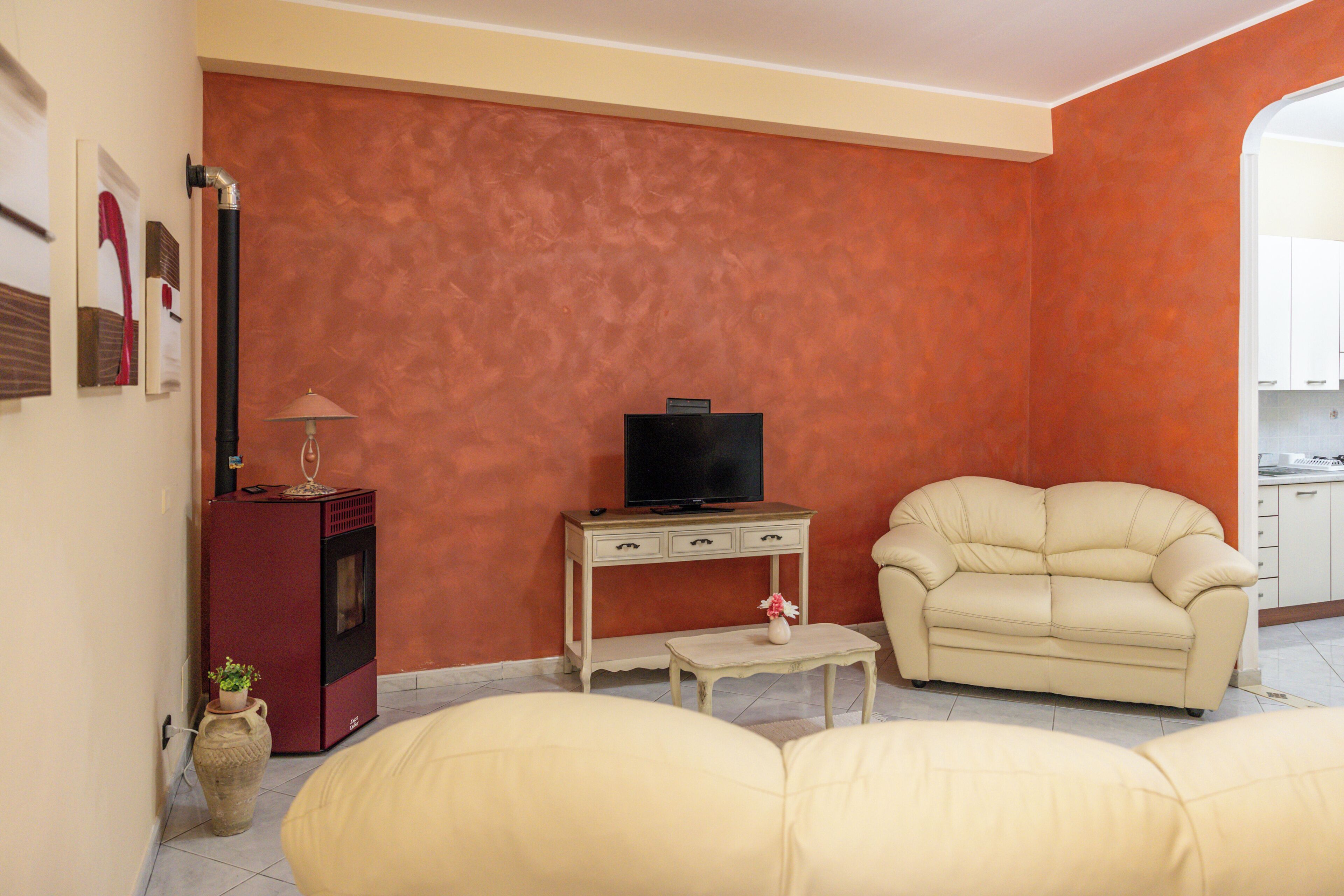 Uma sala de estar com sofá, televisão sobre um suporte, uma mesinha e um armário.