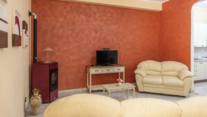 Ein Wohnzimmer mit einer Couch, einem Fernseher auf einem Schrank, einem kleinen Tisch und einem Schrank.