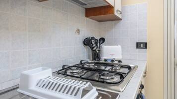 A kitchen with a gas stove, a white countertop, and a wall-mounted electrical outlet.