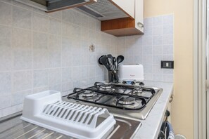 A kitchen with a gas stove, a white countertop, and a wall-mounted electrical outlet. - Casa del Sole - Menfi (Menfi)