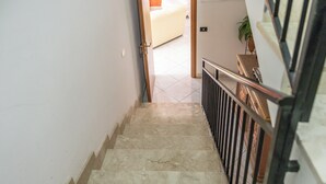 Eine Treppe mit Metallgeländer führt zu einem Zimmer mit einem Bett und einer Pflanze.