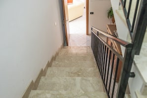 Eine Treppe mit Metallgeländer führt zu einem Zimmer mit einem Bett und einer Pflanze.