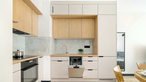 Eine moderne Küche mit weißen Schränken, einer Holz Arbeitsplatte, einem eingebauten Backofen und einem Geschirrspüler.