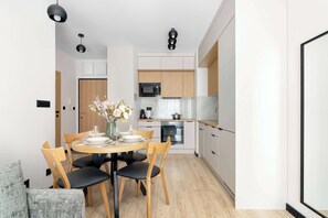 A modern kitchen with white cabinets, a microwave, and a stove. - Cosy Apartment with a Balcony | Parking | Close to Green Spaces (Poznań)