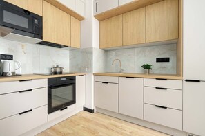 A modern kitchen with white cabinetry, a built-in oven, a microwave, and a sink with a faucet. - Cosy Apartment with a Balcony | Parking | Close to Green Spaces (Poznań)