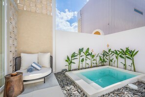 A spa area with a hot tub, a seating area with cushions, and a row of plants. - Villa Temple of Tides (badung)