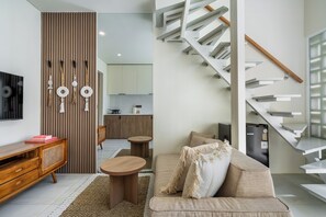 A modern living space with a sofa, coffee table, and a TV on a wooden cabinet. - Villa Temple of Tides (badung)